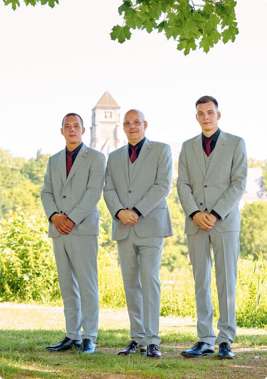 Sven Schmiedel und das Team von Pontura in hellgrauen Anzügen im Park, im Hintergrund ein Kirchturm