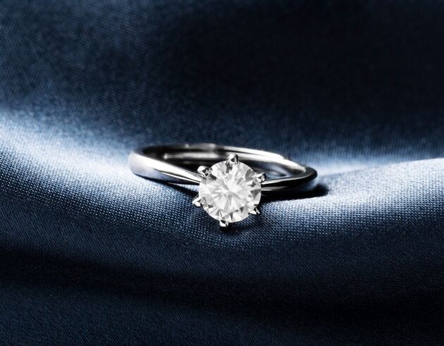 Ring mit Diamant auf dunklem Stoff